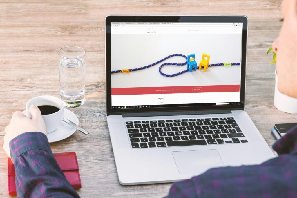 Person viewing a website on a laptop while having coffee at a workspace, representing social media marketing and digital branding services by Techiofy.